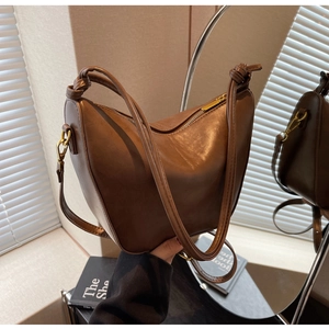 Detail of dark brown leather hobo bag with knotted strap and gold hardware