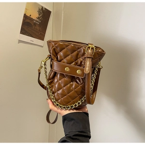 Close-up of brown quilted bucket bag with gold chain strap and detailed PU leather texture