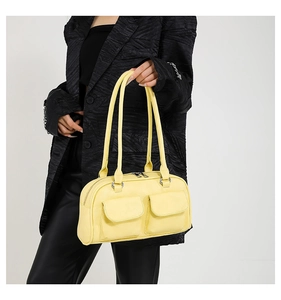Detail of light yellow leather shoulder bag with front flap pockets and silver metal buckles