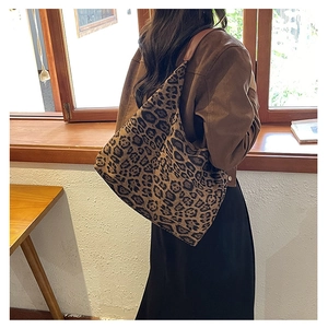 Detail view of the leopard print hobo tote bag with a wide brown leather strap on model