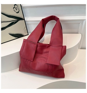 Detail of dark red tote bag featuring concentric circular stitching and textured leather