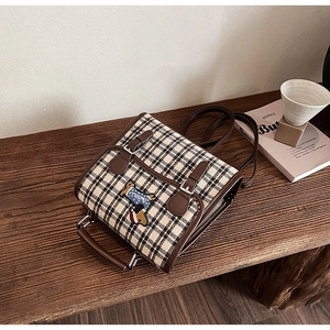 Detail view of British retro plaid backpack with leather trim and dachshund embroidery