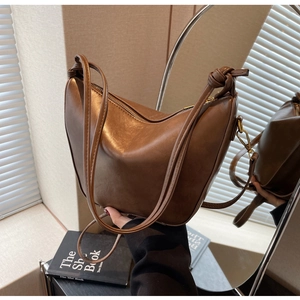 Close-up of dark brown PU leather hobo bag with knotted strap details and zipper closure