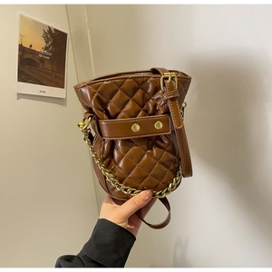 Detail of brown quilted bucket bag with gold chain strap and stitching textures