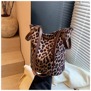 Detail view of leopard print bucket bag with brown leather handles on stairs