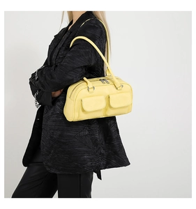 Detail of bright yellow shoulder bag with double front flap pockets on a black suit