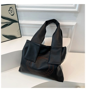 Detailed shot of black litchi leather tote bag with unique orange contrast stitching