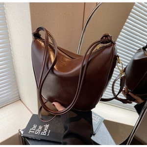 Detail of a dark brown crescent bag with shoulder strap knot and smooth faux leather finish