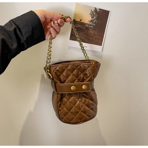 Detailed view of a brown quilted bucket bag with gold chain strap and metal buckles