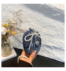 Détail du mini sac en denim bleu avec paillettes argentées et grand nœud en perles