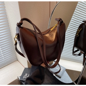 Detail of dark brown leather crescent bag showing knotted strap and zipper closure