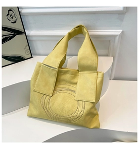 Artistic yellow tote bag detail featuring litchi texture and minimalist circular design