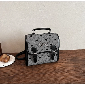 Detail of grey canvas crossbody bag with black bow prints and metal buckle