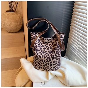 Leopard print bucket bag with brown leather straps displayed in a warm home setting