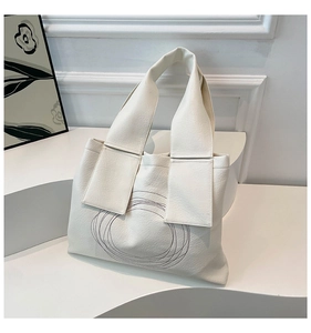 Macro shot of minimalist beige leather tote bag with elegant concentric circle embroidery