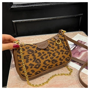Close-up of leopard print shoulder bag featuring gold chain and premium brown leather trim