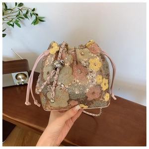 Dettaglio delle paillettes floreali rosa e gialle su una borsa a secchiello con pelle