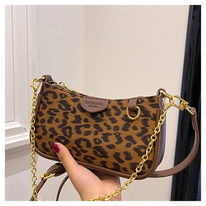 Detail of leopard print baguette bag featuring gold chain and brown leather strap details