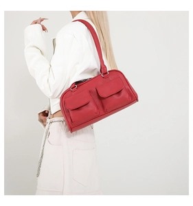 Detail of red leather shoulder bag with two front pockets and pebbled texture