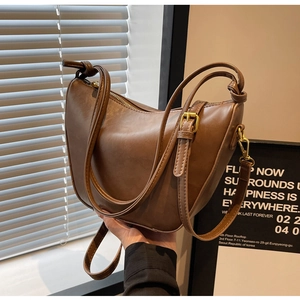 Detail of dark brown vintage crescent bag showing oily leather texture and golden zipper