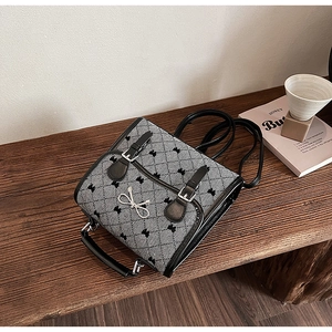 Detail of retro plaid backpack with silver butterfly clasp on a wooden surface