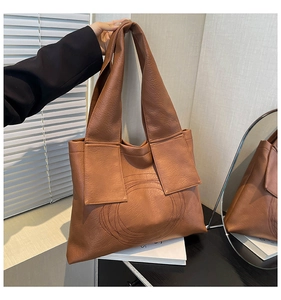 Close-up of dark brown faux leather tote bag with unique round stitching detail and wide strap
