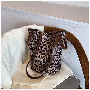 Detail of leopard print bucket bag on a wooden chair with a white blazer