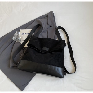 Detail of minimalist black suede backpack with leather base and woven shoulder strap