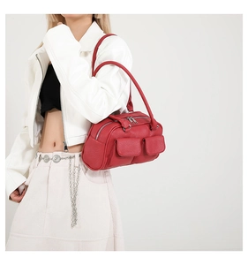 Detail of red vintage-style leather shoulder bag with pockets shown on a model jacket