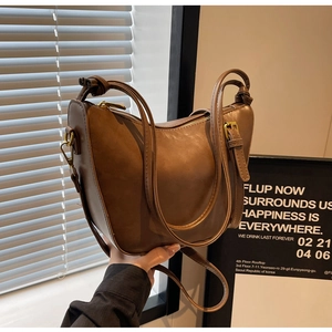 Detail of a brown PU leather bucket bag with retro texture and gold zipper accents