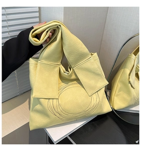 Detail of light yellow tote bag with black circle embroidery and wide shoulder strap