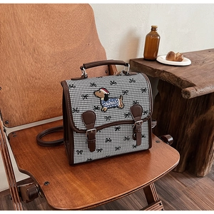Detail of retro houndstooth backpack with dachshund embroidery and leather straps
