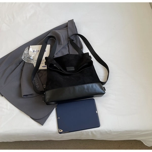Macro shot of minimalist black mixed-texture tote bag with plush and leather panels
