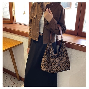 Detail of vintage leopard print tote bag with brown leather handles on shoulder