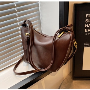 Detail of dark brown retro crescent shoulder bag with knot strap and gold hardware