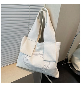 Close-up of litchi texture leather tote bag featuring modern abstract embroidery