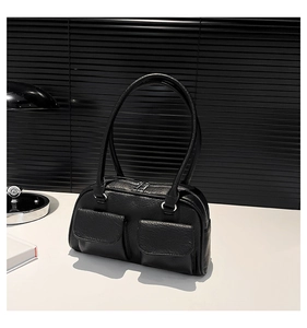 Detail view of black faux leather shoulder bag featuring dual front pockets and zip closure
