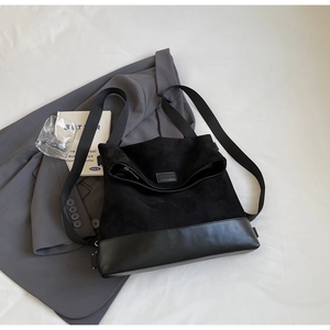Detail of minimalist black mixed-texture crossbody bag with wide strap and embossed logo