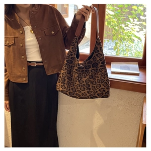 Detail of vintage leopard print hobo tote bag with brown leather strap worn by a model