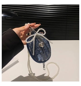 Détail du mini sac en jean avec paillettes, nœud en perles et pendentif cœur