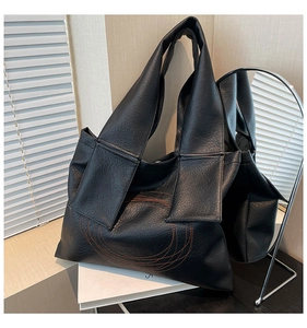 Detailed view of black tote bag featuring unique orange spiral stitching and leather texture