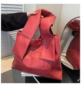 Close-up of red tote bag showing premium litchi texture leather and ring stitching details