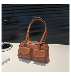 Detail of a brown vintage shoulder bag with dual front pockets and textured faux leather