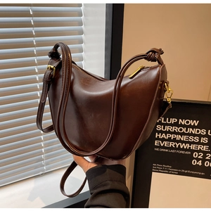 Detail view of vintage dark brown faux leather hobo bag with gold hardware and knot handle