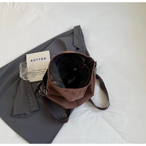 Detail view of large dark brown suede tote bag with adjustable canvas shoulder strap