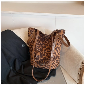 Detail of leopard print tote bag with brown leather straps on a beige chair
