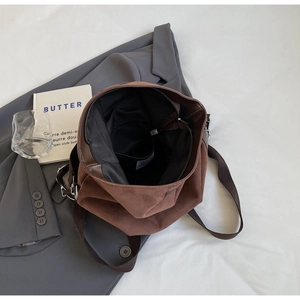 Detail shot showing internal compartments and smooth brown suede texture of the tote bag