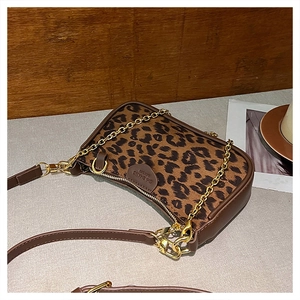Detail of leopard print handbag with golden chain and heart brand tag on retro table