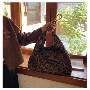 Detail shot of a large leopard print tote bag placed by a window in a lifestyle setting