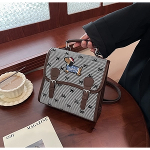 Detailed view of vintage houndstooth backpack with dog embroidery and brown leather trim